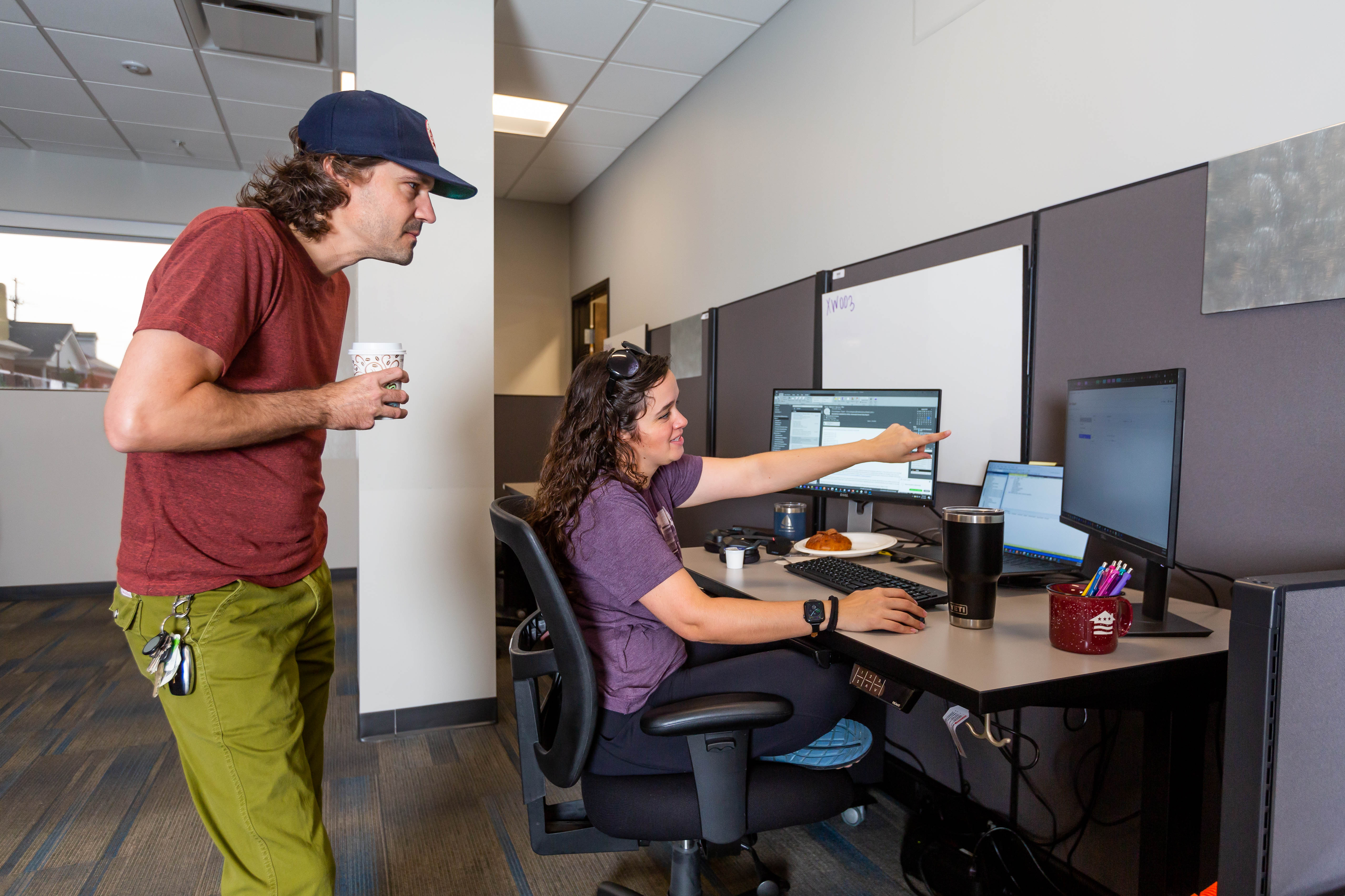 A woman pointing at a computer while a man looks at the screen