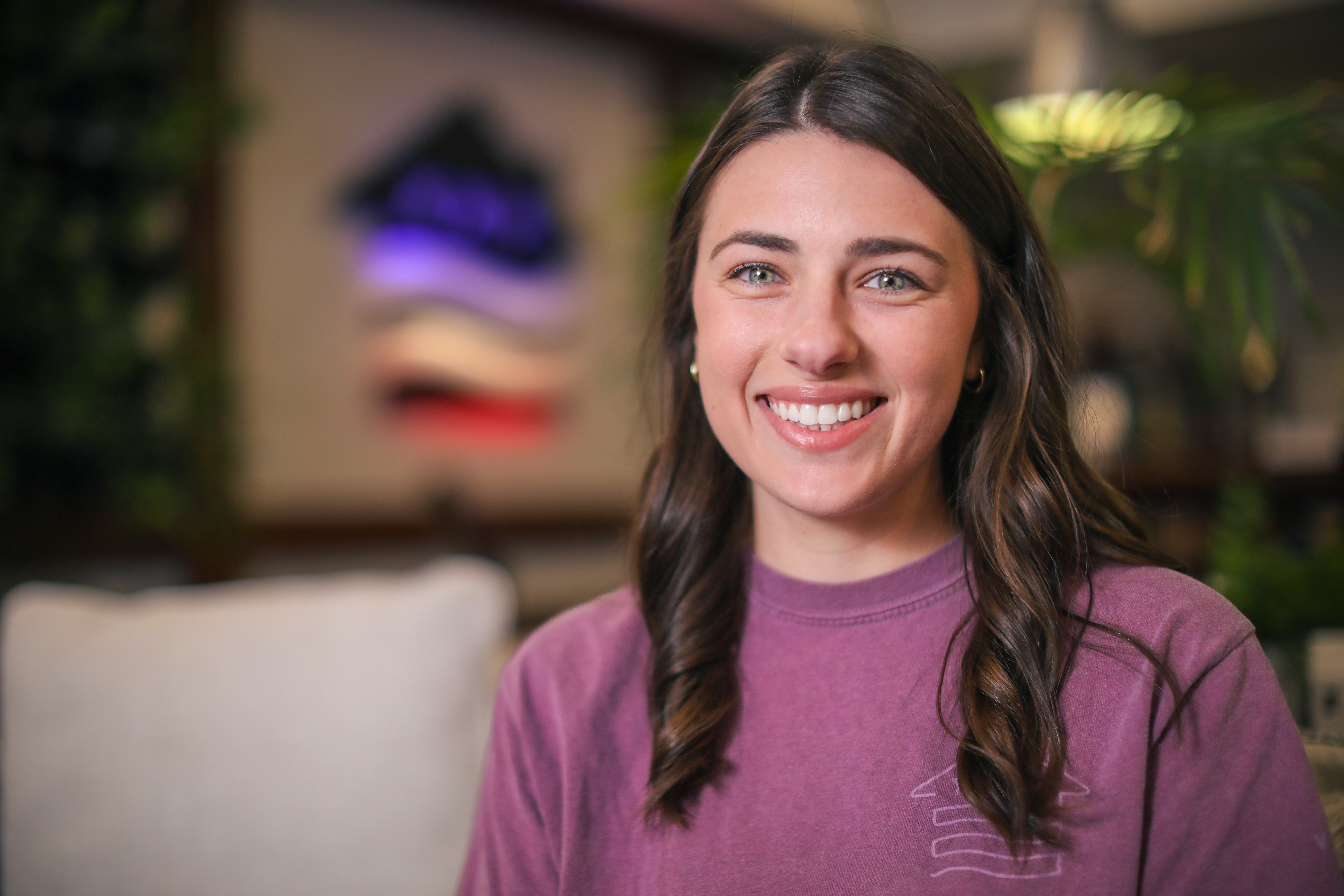 A woman smiling with the VU logo behind her