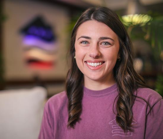 A woman smiling with the VU logo behind her