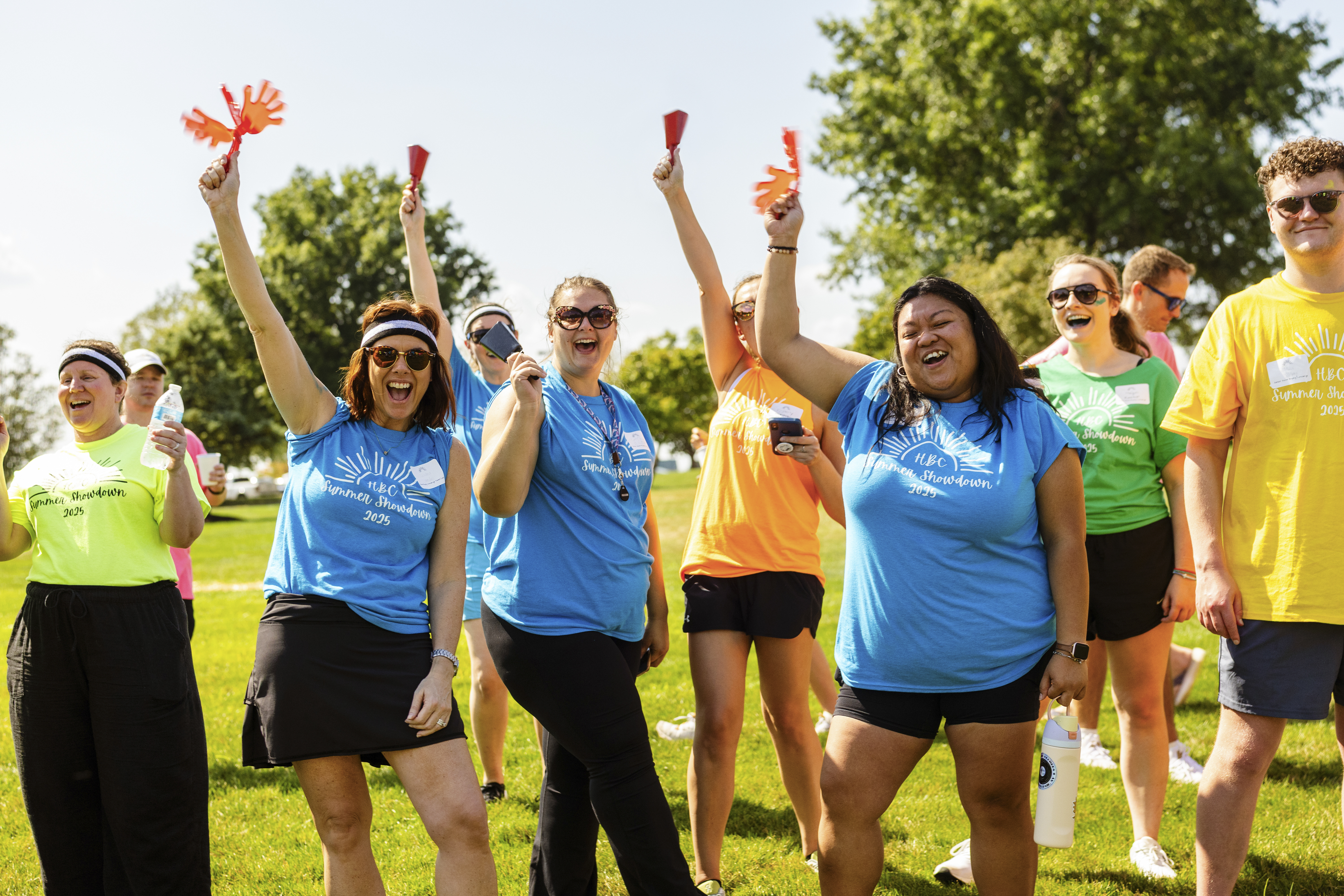 Group of employees raising their arms in celebration outside
