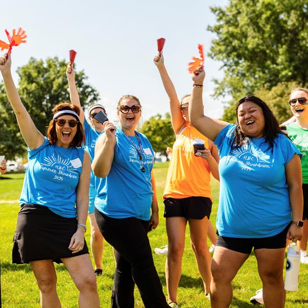 Group of employees raising their arms in celebration outside