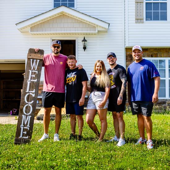 Group of VUers standing outside a house.