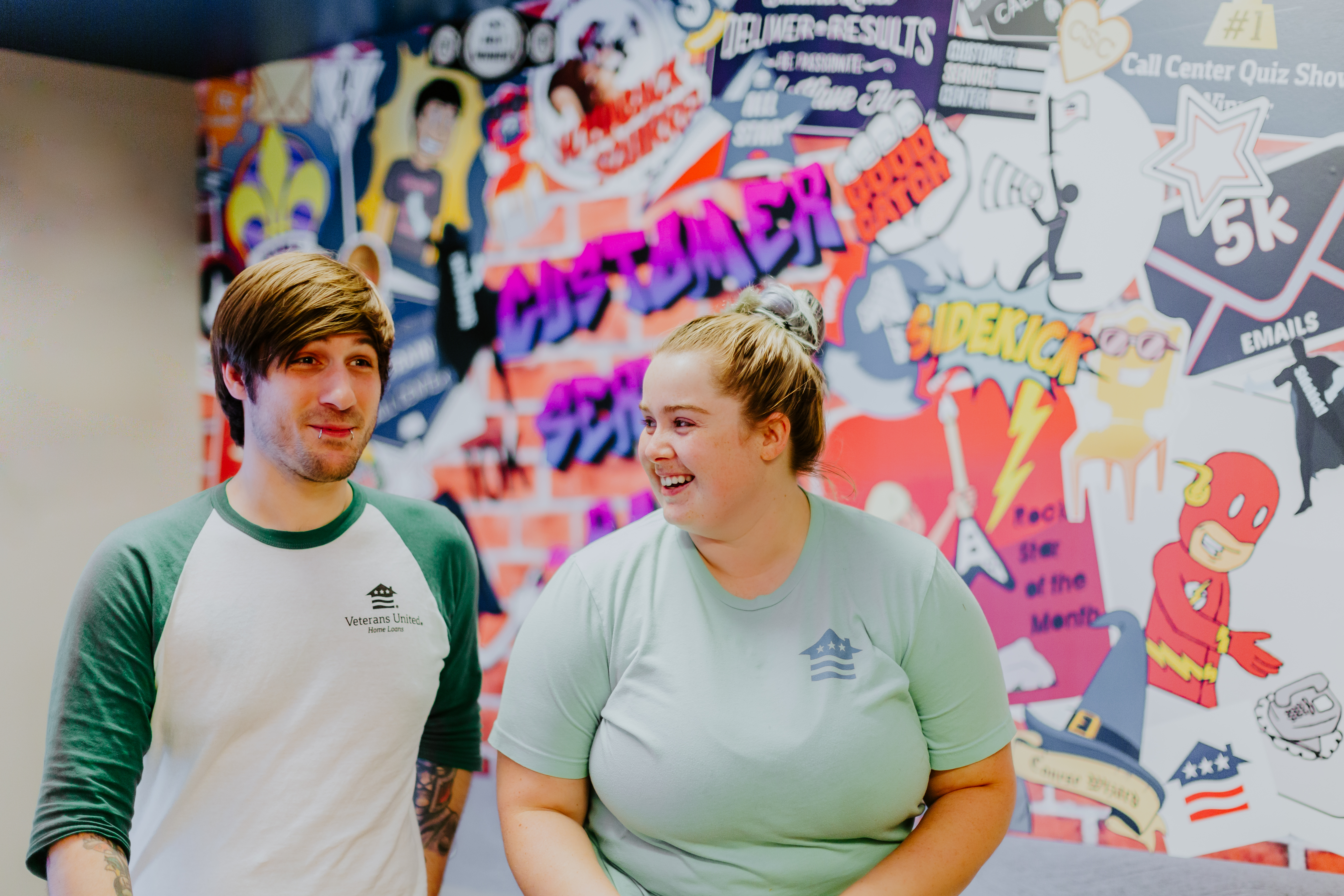 A man and woman in front of a wall filled with positive graffiti