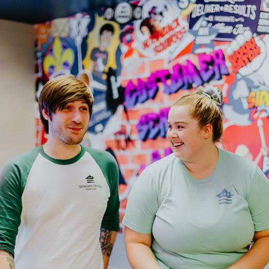 A man and woman in front of a wall filled with positive graffiti