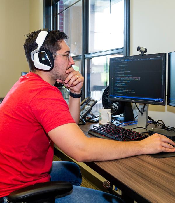 A man looking at two computer monitors